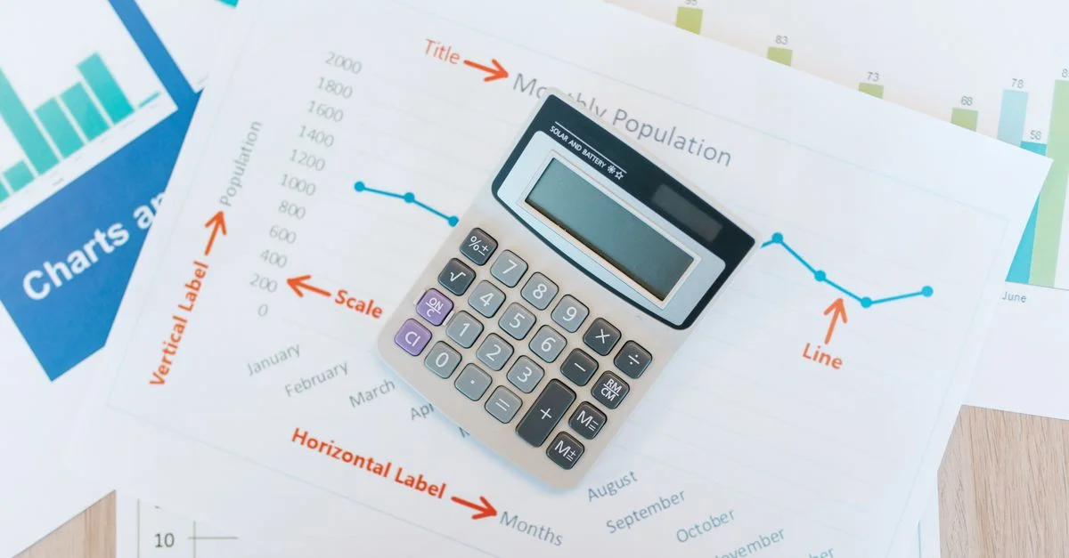 Calculadora colocada sobre gráficos y informes financieros que muestran análisis de datos y documentación empresarial.