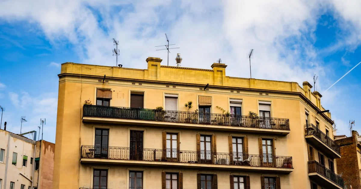 Encantadora vista de un edificio de apartamentos histórico en Barcelona, que muestra una arquitectura clásica contra un cielo azul.