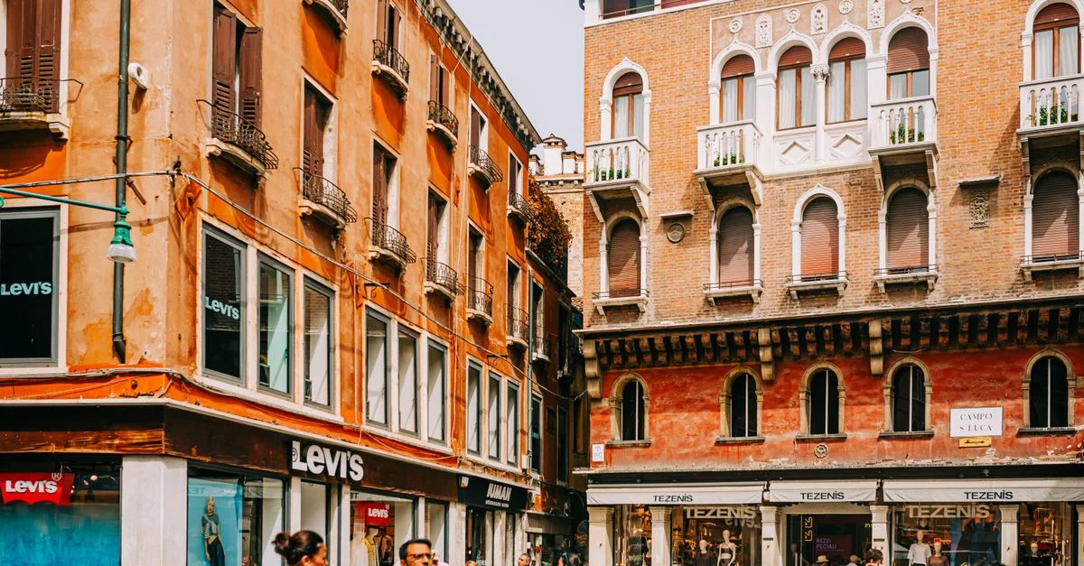 Vibrante escena callejera en Venecia, con edificios históricos y compradores bulliciosos que crean un ambiente animado.