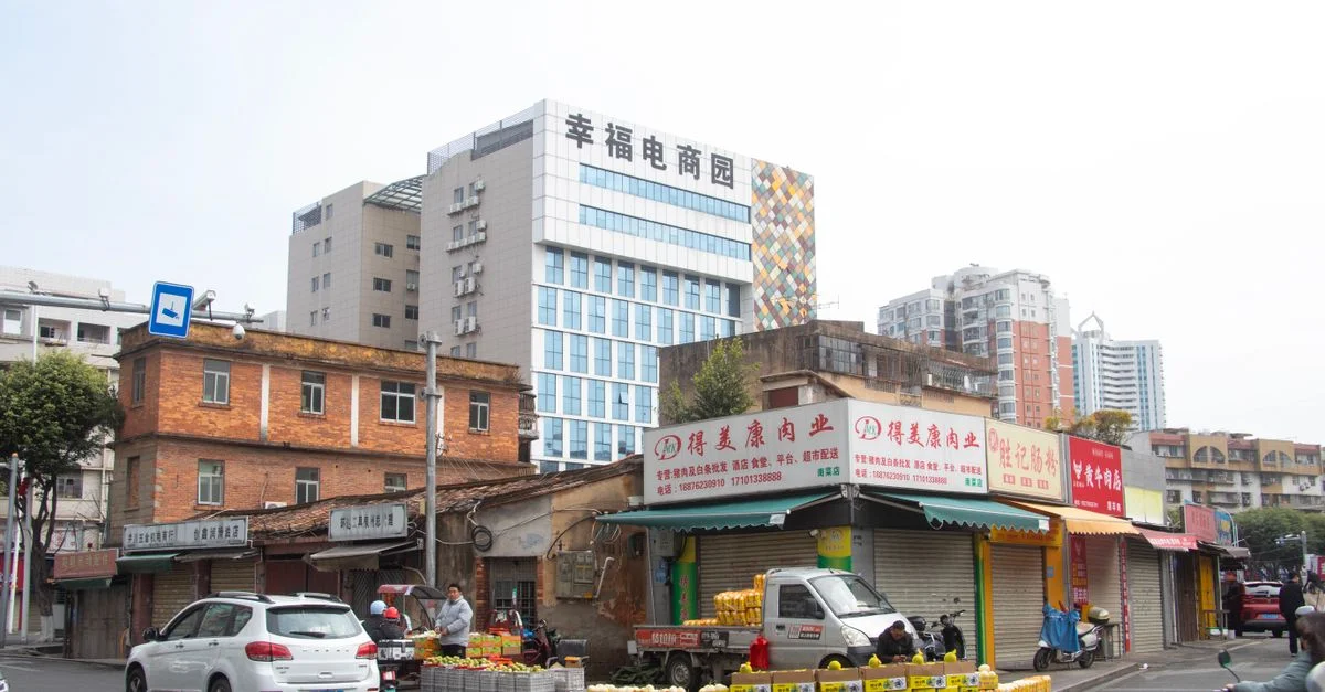 Escena callejera de Quanzhou, en Fujian, China, que muestra puestos de mercado locales, edificios modernos y vehículos.