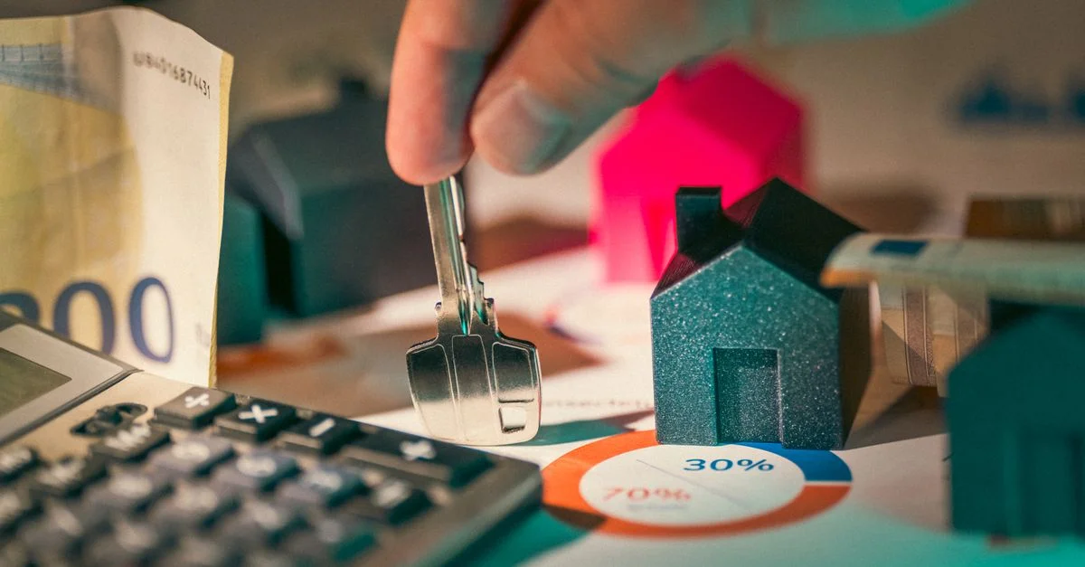 Un primer plano de la planificación financiera inmobiliaria con llaves, calculadora y dinero.