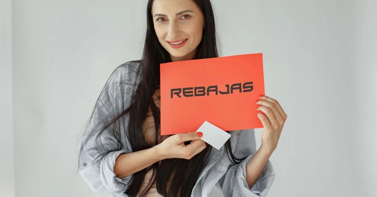 Mujer sonriente sostiene un cartel rojo 'REBajas', promoviendo ventas y descuentos.